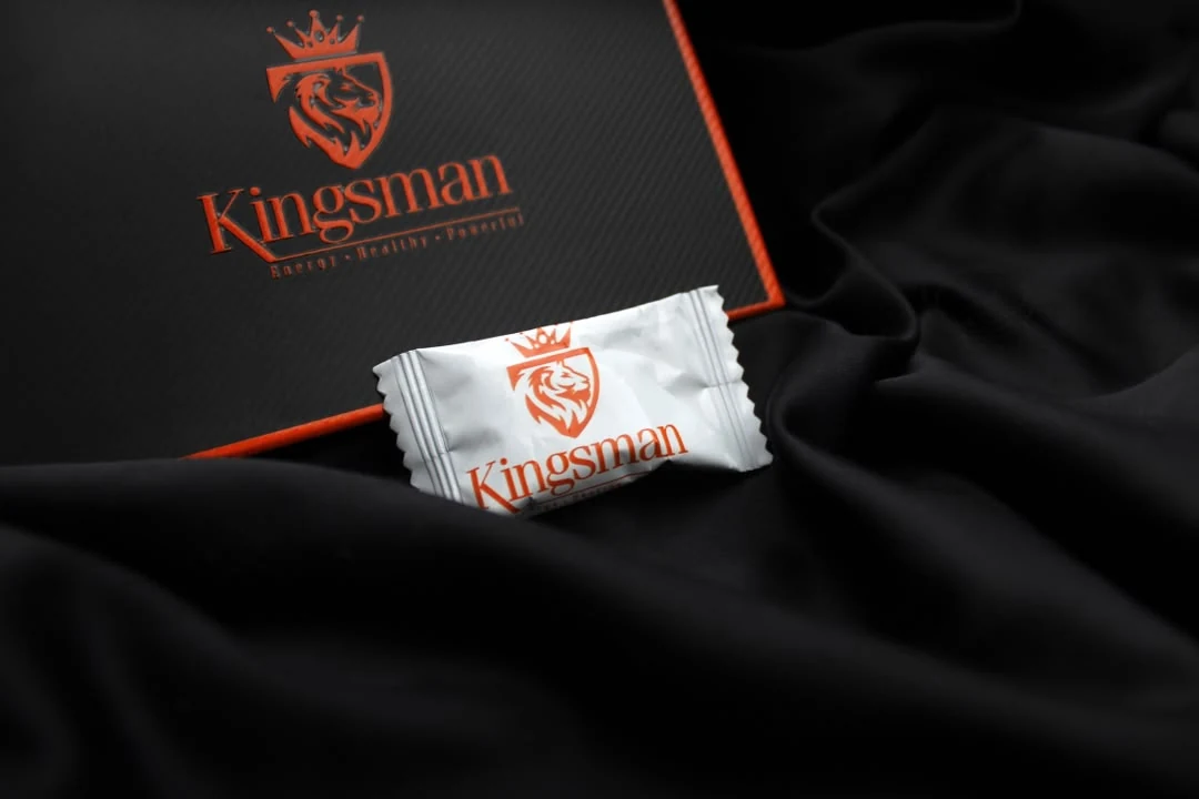 Coffret Kingsman noir au liseré orange et son bonbon, sur satin noir