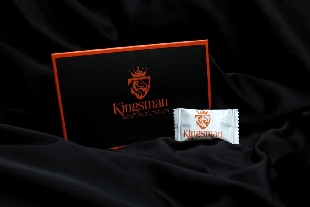 Coffret Kingsman posé sur un satin noir, un bonbon devant