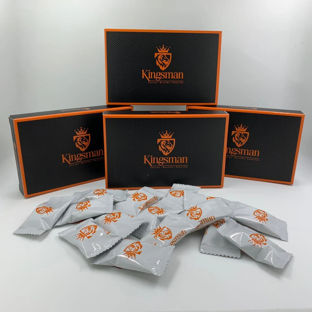 Trois coffrets Kingsman noirs au liseré orange et une poignée de bonbons en sachets blancs