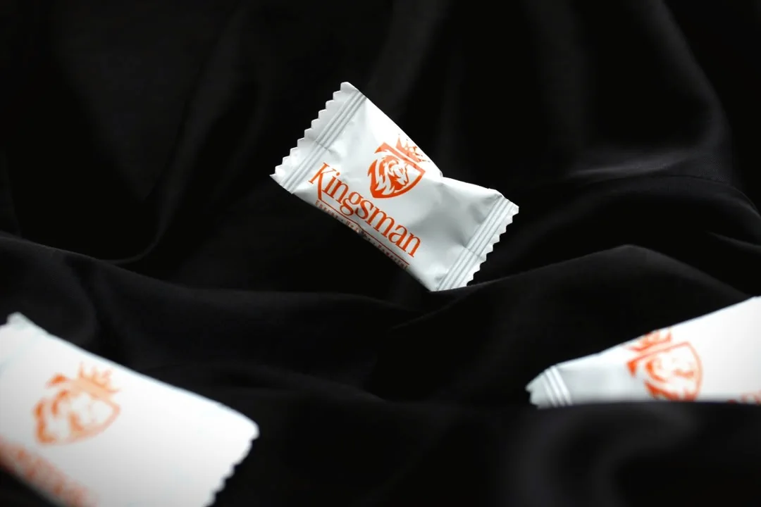 Bonbons Kingsman dans leurs sachets blancs sur un satin noir